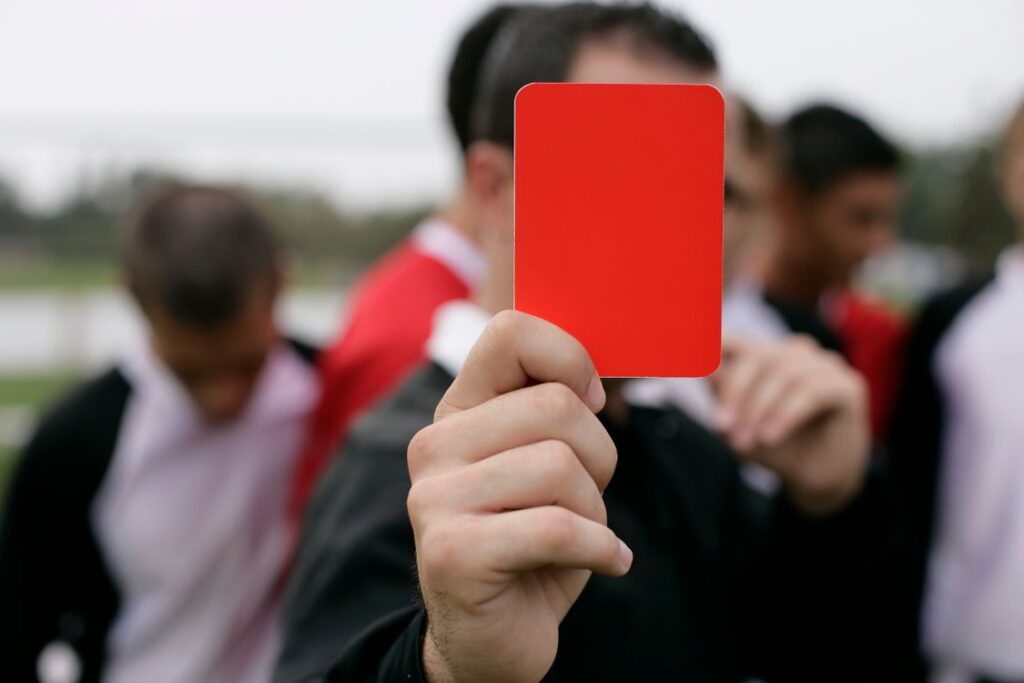 Árbitro mostrando cartão vermelho a jogadores durante partida de futebol na Copa 2026