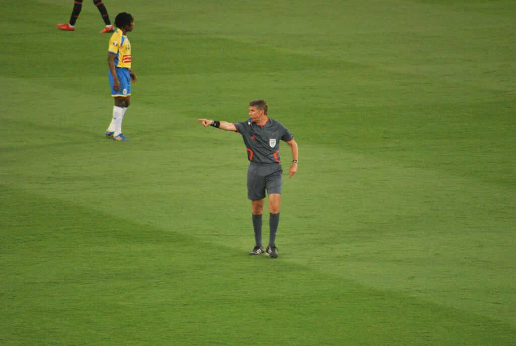 Árbitro mostrando cartão vermelho a jogador durante partida de futebol, determinando expulsão imediata