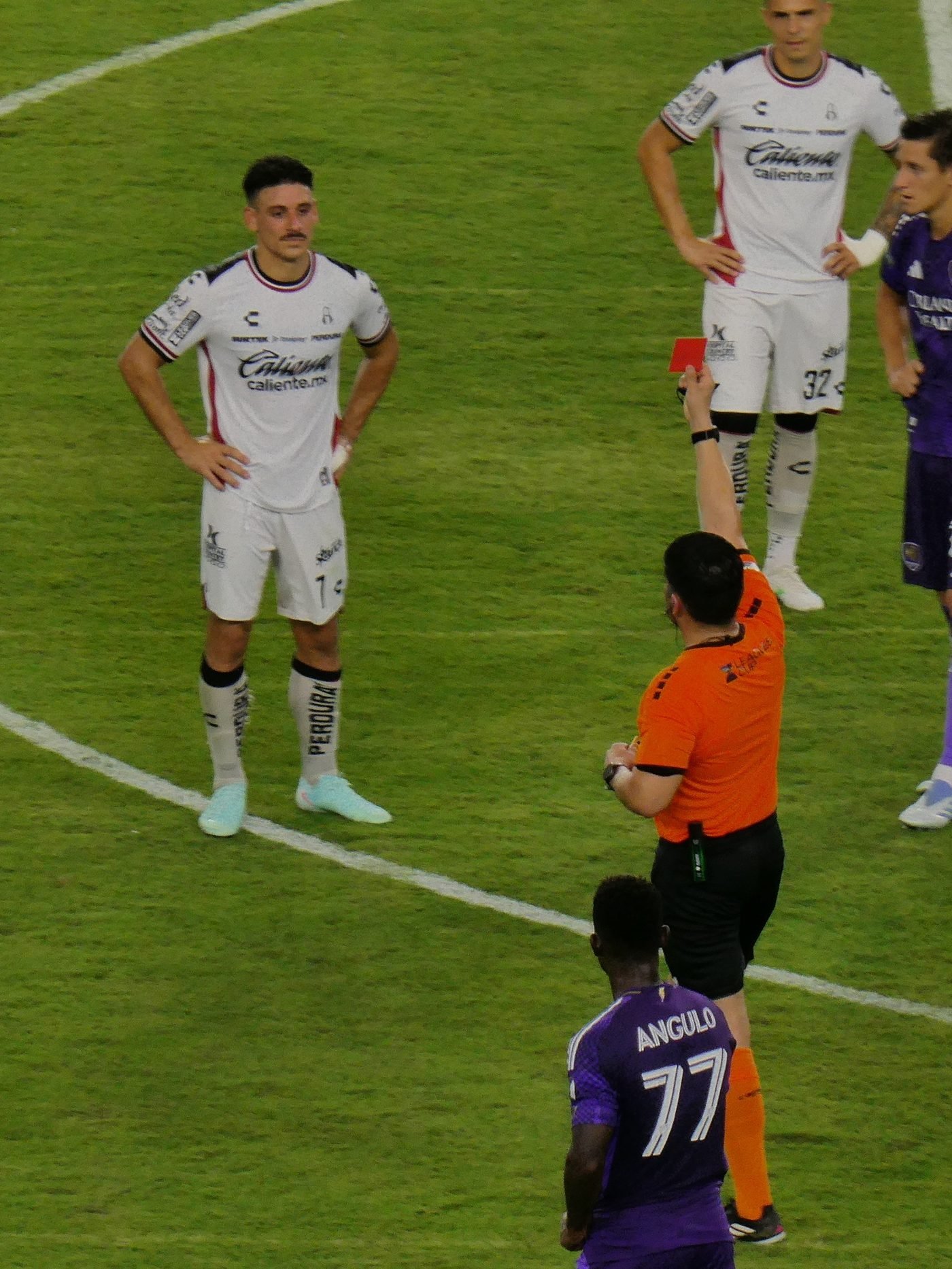 Árbitro mostrando cartão vermelho durante partida de futebol