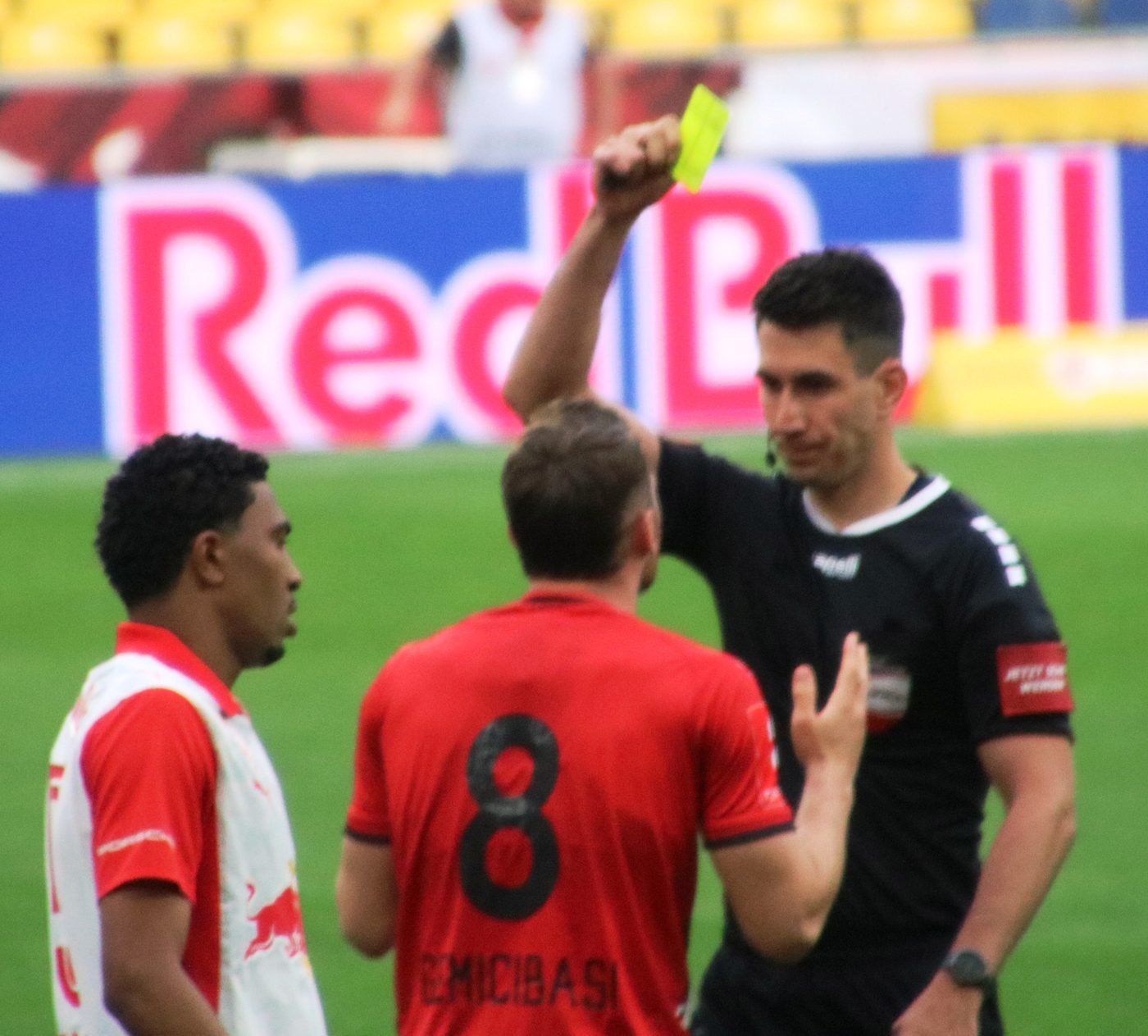 Árbitro em ação durante partida de futebol, contexto de aplicação de cartão amarelo
